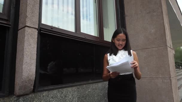 Fiatal gyönyörű üzleti nő női lány portré pillantást dokumentumok áll a háttérben irodaház szabadtéri — Stock videók