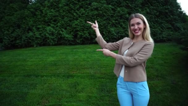 Jonge mooie blonde vrouw punt vingers handen om lege ruimte — Stockvideo