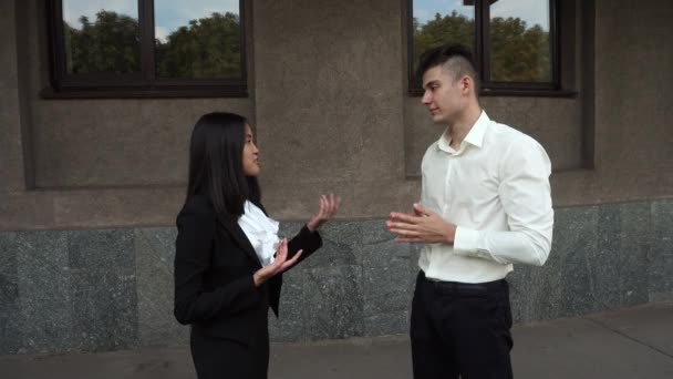 Genç güzel iş kadın kız ve beyaz erkek portre Talk üzerinde arka plan ofis binası açık duruyor pazarlık — Stok video