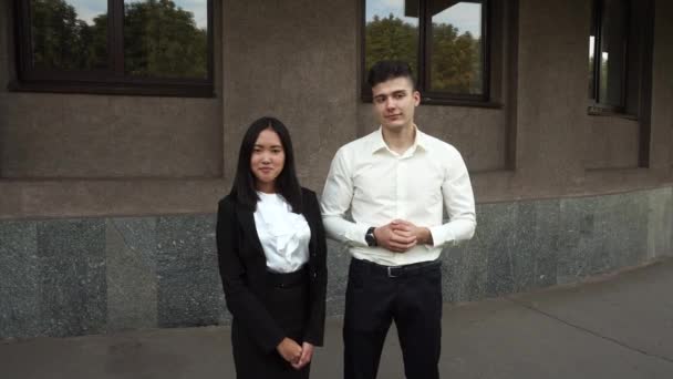 Jeune belle femme d'affaires fille féminine et caucasien portrait masculin regarder caméra se tient sur fond immeuble de bureaux en plein air — Video