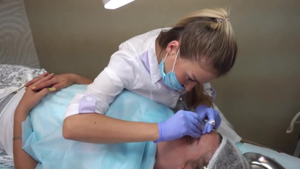 Esteticista hace procedimiento paciente dibuja cejas Mikrobleyding cliente permanente tatuaje, reconstrucción de cejas, pigmentación micro — Vídeo de stock