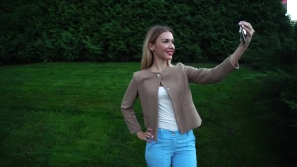 Joven hermosa rubia hembra hace selfie teléfono sonriendo posando — Vídeo de stock