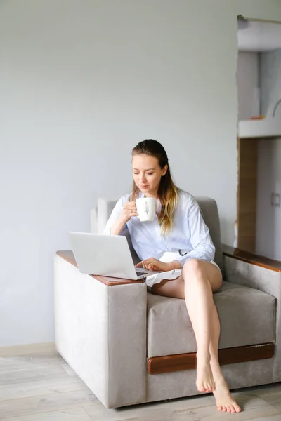 Chica joven que trabaja con el ordenador portátil en casa y beber café. — Foto de Stock