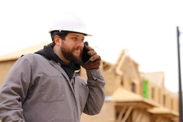 Кавказький будівельник розмовляє за допомогою смартфона на будівельному майданчику.. — стокове фото