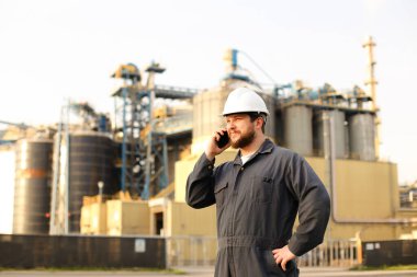 Endüstriyel direktör, fabrikanın önünde VHF telsiziyle konuşuyor..