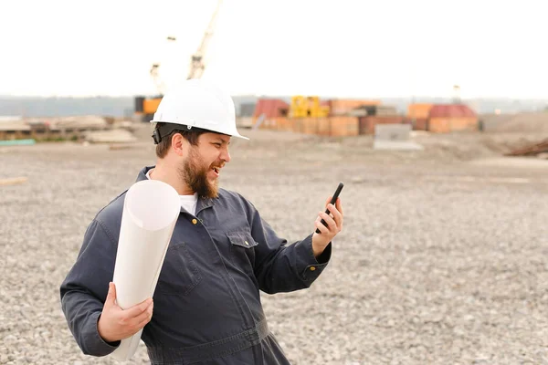 Ingeniero de construcción estadounidense sosteniendo walkie talkie VHF y papeles en el sitio de construcción. —  Fotos de Stock