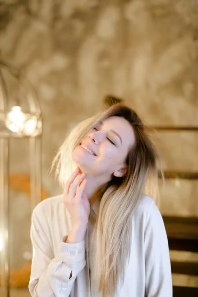 Portrait de jeune fille blonde avec les yeux fermés assis sur des escaliers en bois. — Photo