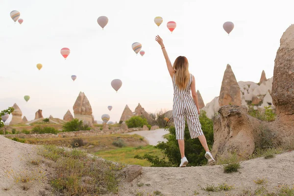 Back view girl standing, hot air balloons and rocks in background, Cappadocia. — Stock Photo, Image
