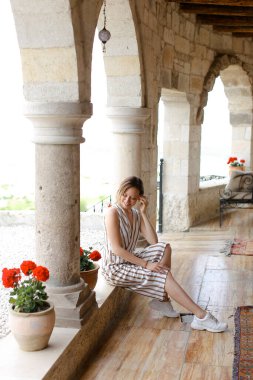 Oturma odasının kemerinde oturan beyaz kız sütunlara yaslanıyor..