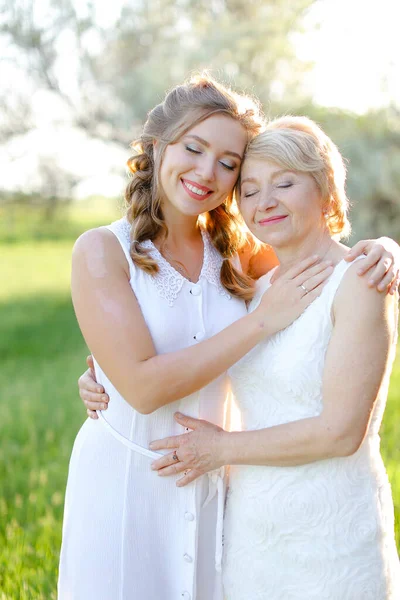 Ritratto di ragazza che abbraccia la madre fuori e indossa un vestito bianco. — Foto Stock