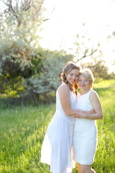 Caucasiano menina abraçando mãe fora e vestindo vestido branco. — Fotografia de Stock