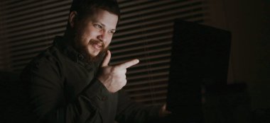 Genç adam bilgisayarla konuşuyor ve işaret parmağını gösteriyor..