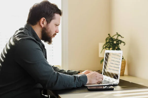 Joven hombre de negocios barbudo que trabaja en la oficina, mirando la pantalla del ordenador portátil. — Foto de Stock