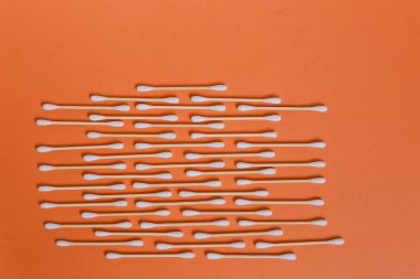 Turuncu arka planda birçok pamuklu tomurcuk sıralanır.