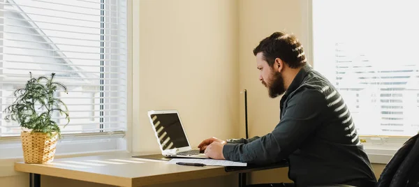 Finanziere maschio seduto alla scrivania e utilizzando il computer portatile al gabinetto. — Foto Stock