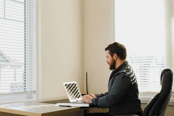 Sviluppatore web maschile seduto alla scrivania e utilizzando il computer portatile al gabinetto. — Foto Stock