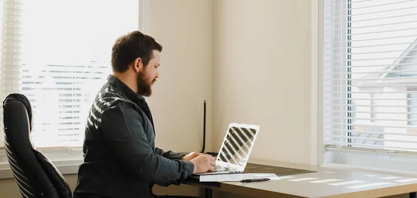 Hakcer computer maschile seduto alla scrivania e utilizzando il computer portatile al gabinetto. — Foto Stock