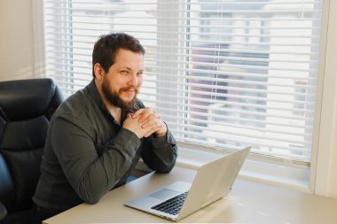 Kabinede dizüstü bilgisayarla çalışan gülümseyen bilgisayar korsanı.