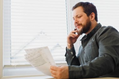 Bakanlar Kurulu 'nda evrak okuyan, elinde kağıt ve kalem tutan bir borsacı..