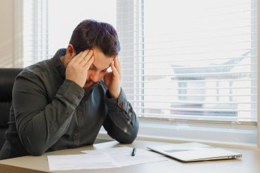 Ofiste belgelerle çalışan, bilgisayarını kapatmış bir pazarolog..