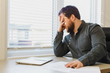 Ofiste belgelerle çalışan yorgun iş adamı, masadaki bilgisayarı kapatmış..
