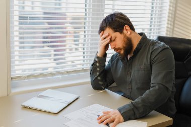 Ofiste belgelerle uğraşmaktan yorgun düşmüş bir yönetici, masadaki bilgisayarı kapatmış..