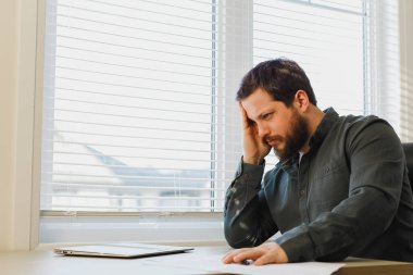 Ofiste belgelerle çalışan yorgun girişimci, masadaki bilgisayarı kapatmış..