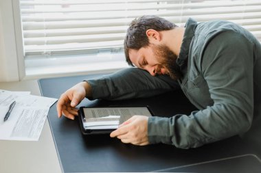 İş adamı işyerinde uyuyor, tablet masanın üstünde..