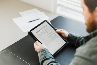 Tablette elekronik kiralama sözleşmesi okuyan adam.