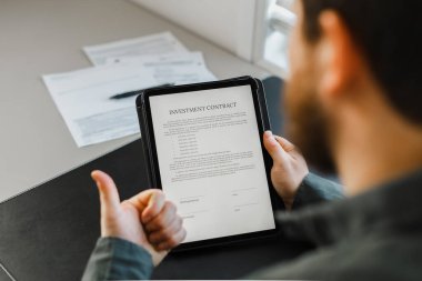 Tablette şablon yatırım sözleşmesi okuyan adam.