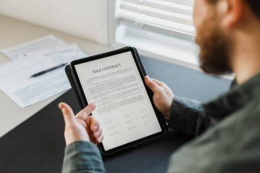 Tablette araba satışı sözleşmesi gösteren ve baş parmak gösteren bir adam..