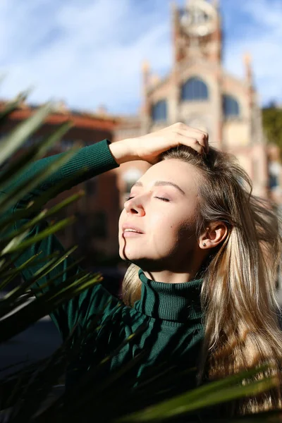 Porträt eines kaukasischen Mädchens mit Palmblatt, altes Gebäude im Hintergrund. — Stockfoto