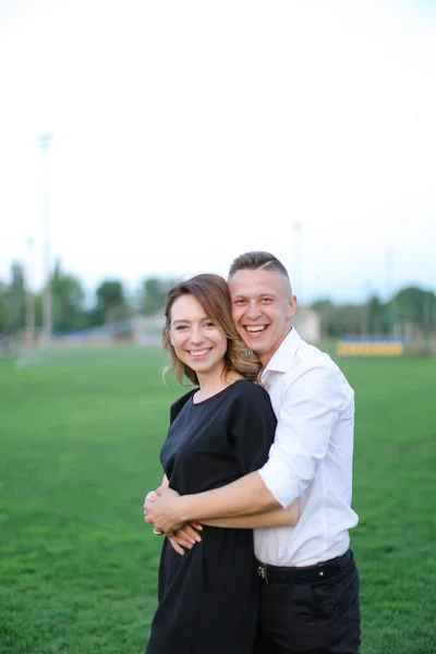 Jonge man knuffelen vrouw op voetbalveld. — Stockfoto