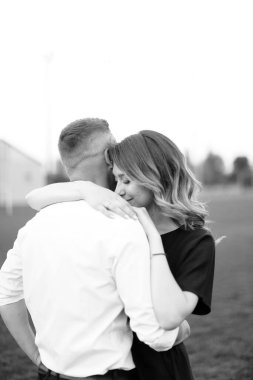 Siyah beyaz bir fotoğraf. Genç bir kadın. Arka planda kocasını kucaklıyor..