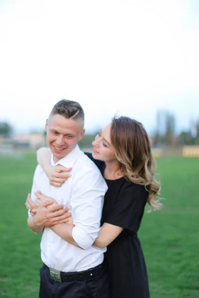 Jong gelukkig vrouw knuffelen man op groen voetbal veld. — Stockfoto