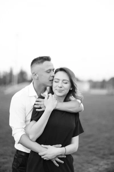 Czarno-białe zdjęcie męża całującego żonę na zewnątrz. — Zdjęcie stockowe