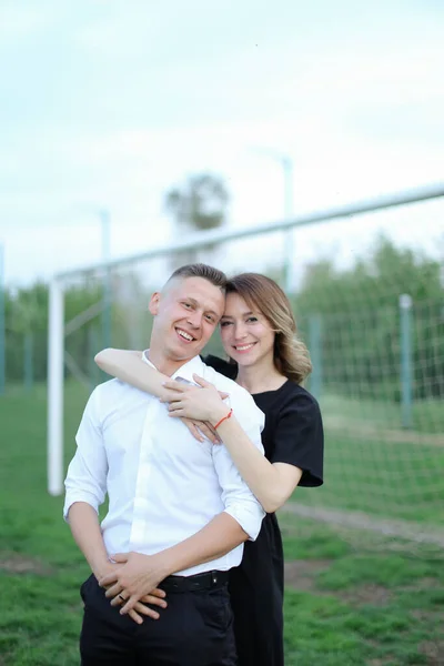 Young woman hugging man, football goal in background — Stock Photo, Image