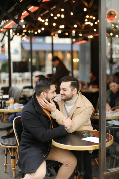 Caucasiens souriants gays assis au café et câlins. — Photo