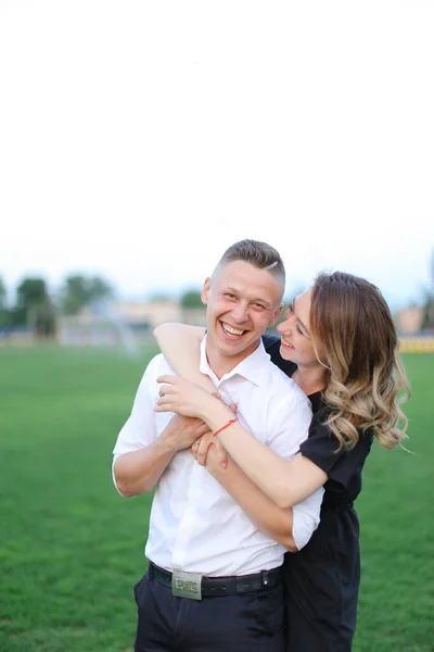 年轻的妻子在足球场拥抱丈夫. — 图库照片