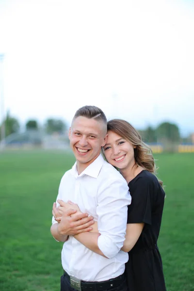 Young woman hugging man on green football field. — Stock Photo, Image