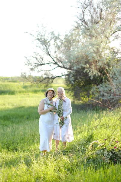 Retrato da vovó com a filha andando ao ar livre, vestindo vestidos brancos. — Fotografia de Stock