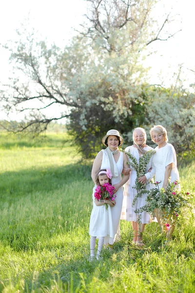 Vovó caucasiana em vestido branco com filhas e neta fora. — Fotografia de Stock