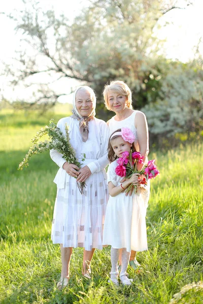 Caucasian granny in white dress with daughter and granddaughter outside. — Stock Photo, Image