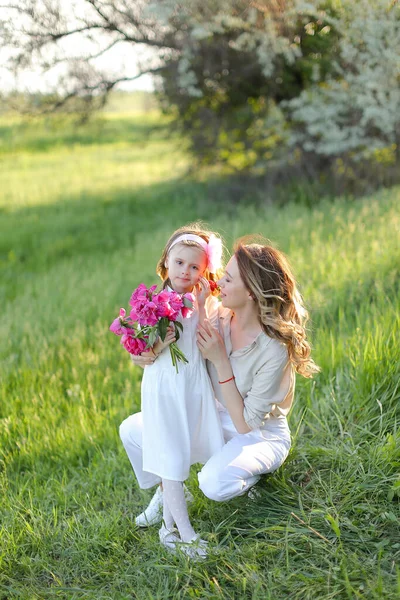 Young mother sitting with little daughter on grass. — Stock Photo, Image