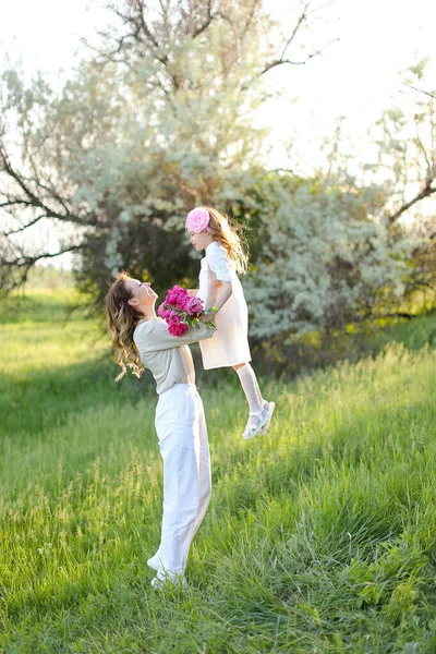 Jovem loira mãe segurando pequena filha na grama. — Fotografia de Stock