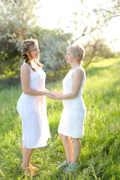 Menina caucasiana segurando as mãos mãe fora e vestindo vestido branco. — Fotografia de Stock