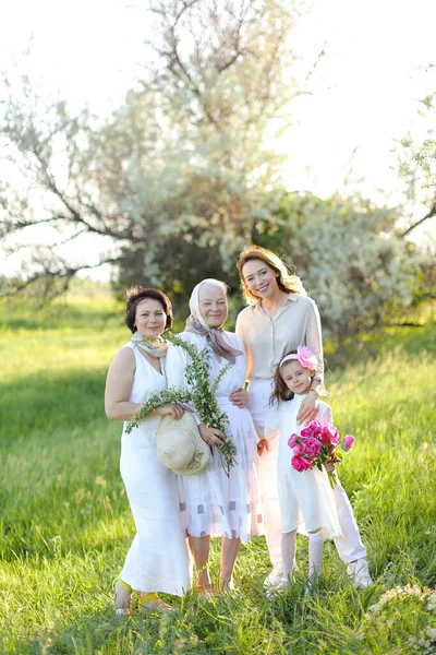 Vovó caucasiana em vestido branco com filha e netas ao ar livre. — Fotografia de Stock