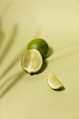 Taze kireç ve dilim, açık yeşil arka planda izole edilmiş.