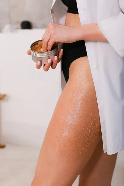 Mujer aplicando un exfoliante nutritivo en el cuerpo sobre el fondo del baño, primer plano — Foto de Stock