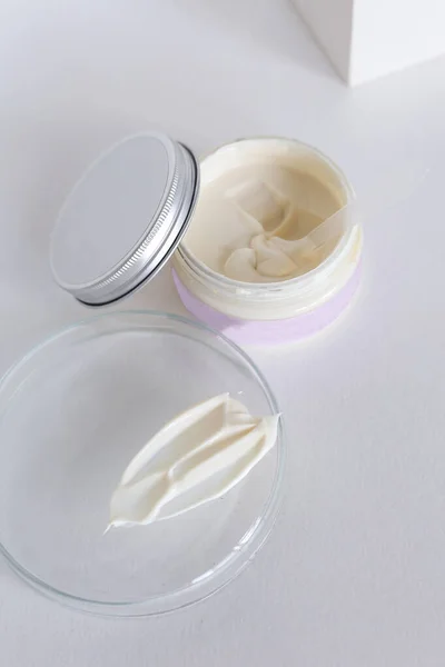 Crema cosmética hidratante sobre fondo neutro con salpicaduras de leche — Foto de Stock